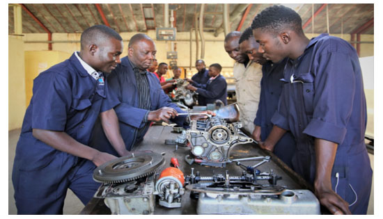 Advanced level MVM students assembling a motor vehicle engine parts with the help of their instructor during the practical lessons