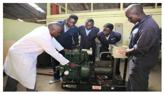 Mr. Peter Odhiambo illustrating how a power plant machine operates to students during a practical session in the automotive workshop.